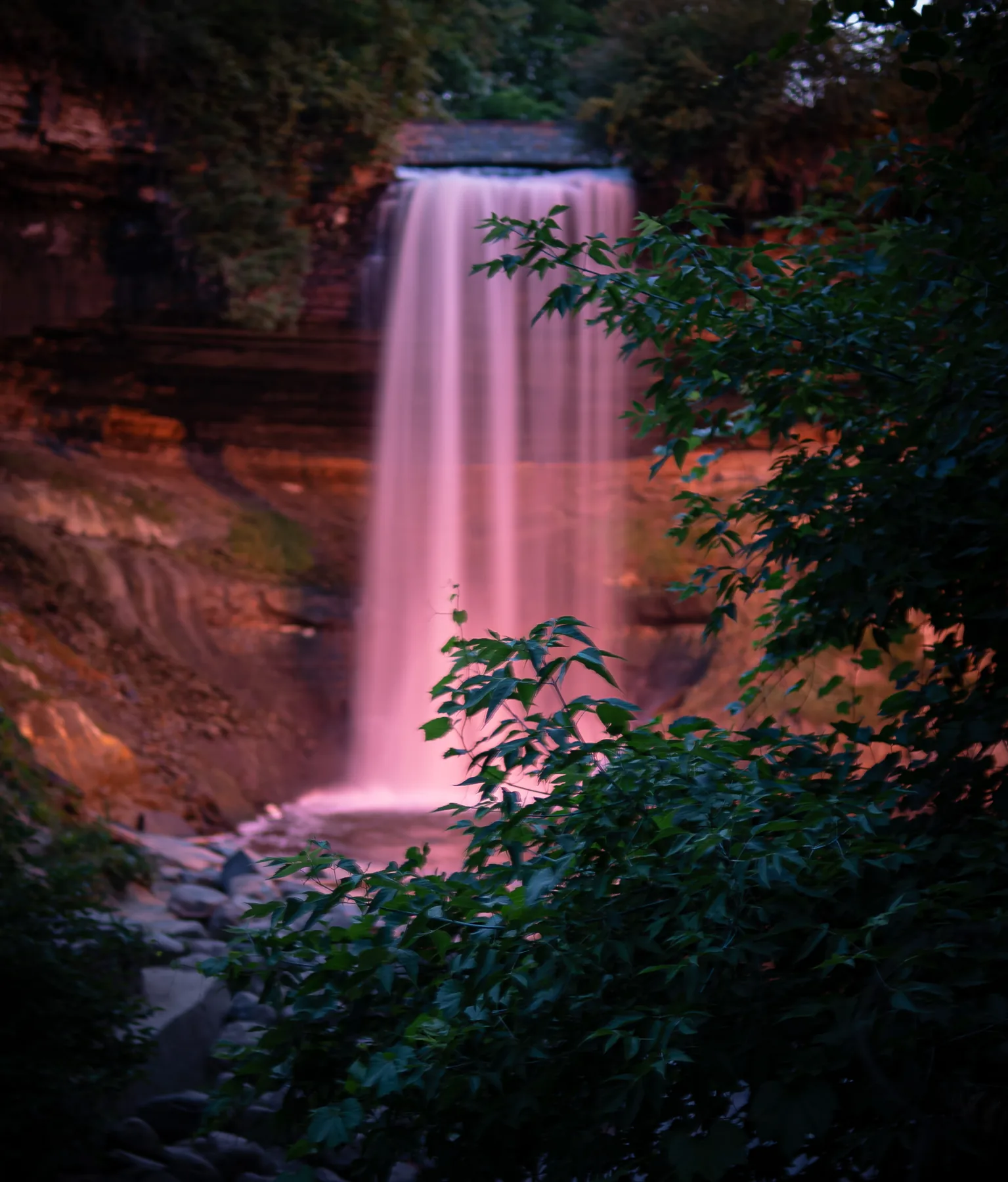 Water falling over sandstone into green